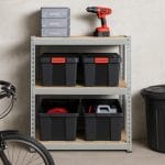 Box porta attrezzi neri con chiusura arancione riposti su scaffale da garage