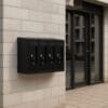 Cassetta postale nera 4 scomparti fissata al muro esterno di condominio moderno