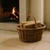 Cesto in vimini con legna davanti al camino acceso