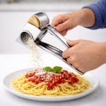 grattugia manuale Grattugia manuale in acciaio inox in uso su pasta con formaggio grattugiato