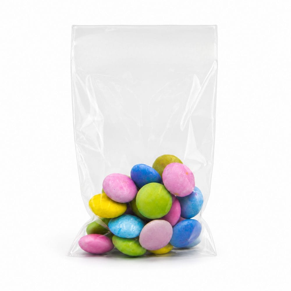 Sacchetto trasparente in cellophane lucido riempito con confetti e caramelle colorate su sfondo bianco