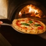 pala pizza coreografica Pala pizza in acciaio inox che estrae una pizza dal forno a legna