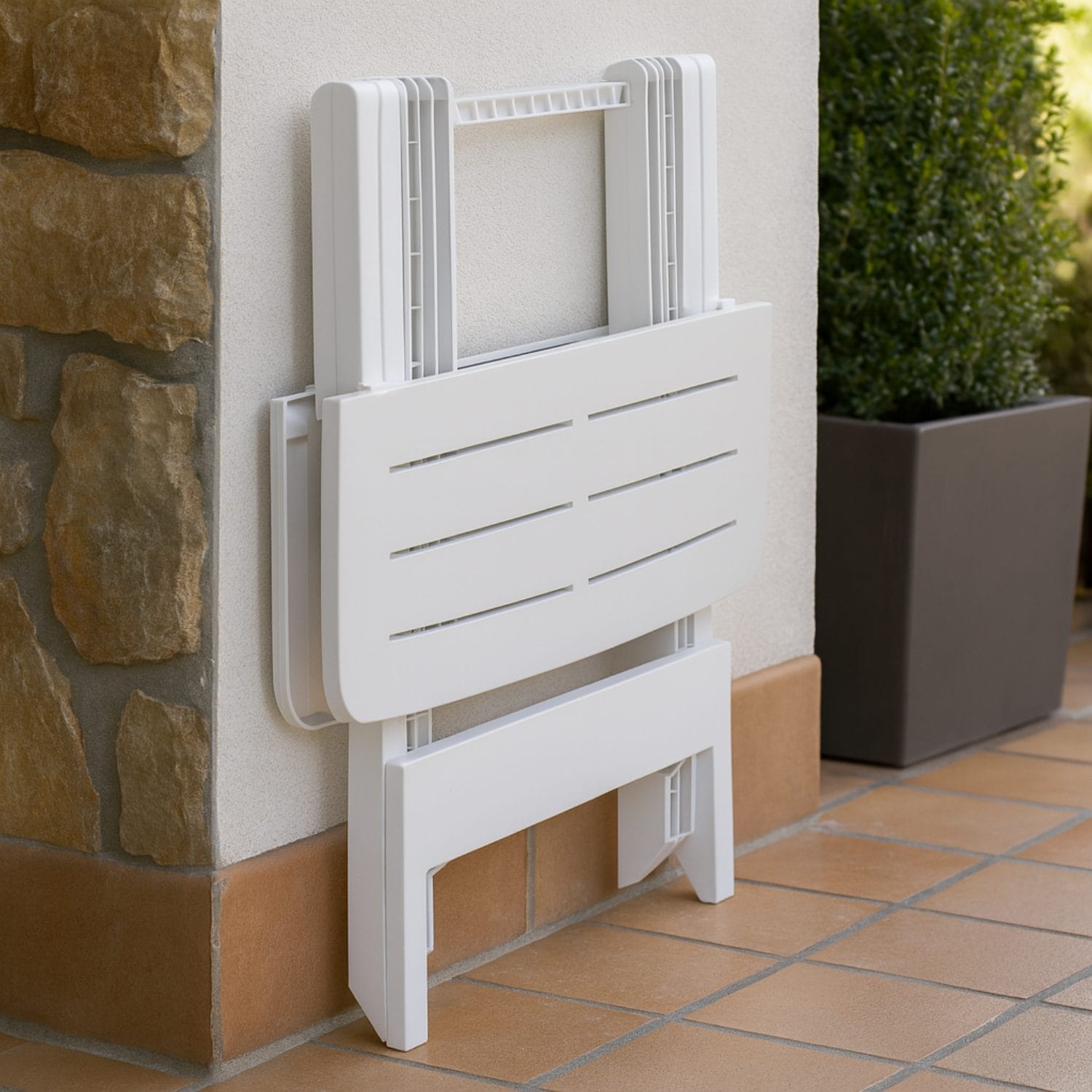 Tavolino da giardino pieghevole appoggiato al muro in posizione chiusa