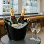 Secchiello portaghiaccio ovale nero con bottiglie di champagne e calici