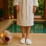 Pantofole monouso chiuse per piscina e area wellness Persona con accappatoio bianco e ciabatte monouso chiuse in spugna di cotone a bordo piscina