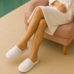 Ciabatte monouso chiuse per SPA, hotel e centri benessere Persona con accappatoio che indossa ciabatte monouso chiuse bianche in spugna di cotone in area relax SPA