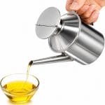 Oliera in acciaio inox per olio e condimenti Oliera in acciaio inox 500 ml inclinata mentre versa olio in una ciotola di vetro
