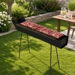Barbecue a canaletta per arrosticini con numerosi spiedini su brace, posizionato in giardino con gambe pieghevoli