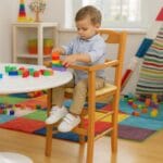 Bambino gioca su seggiolone in legno di faggio ciliegio con seduta in paglia intrecciata