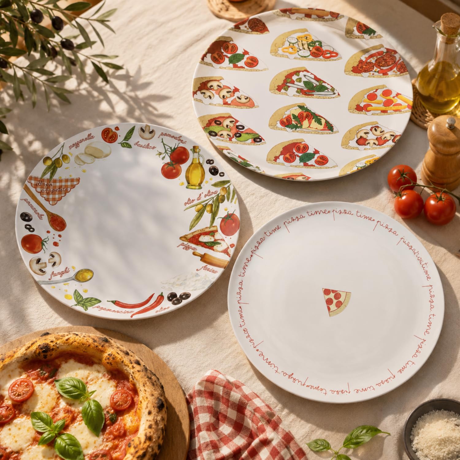 Tre piatti da pizza decorati disposti su una tovaglia chiara accanto a pomodori freschi e una pizza margherita fumante