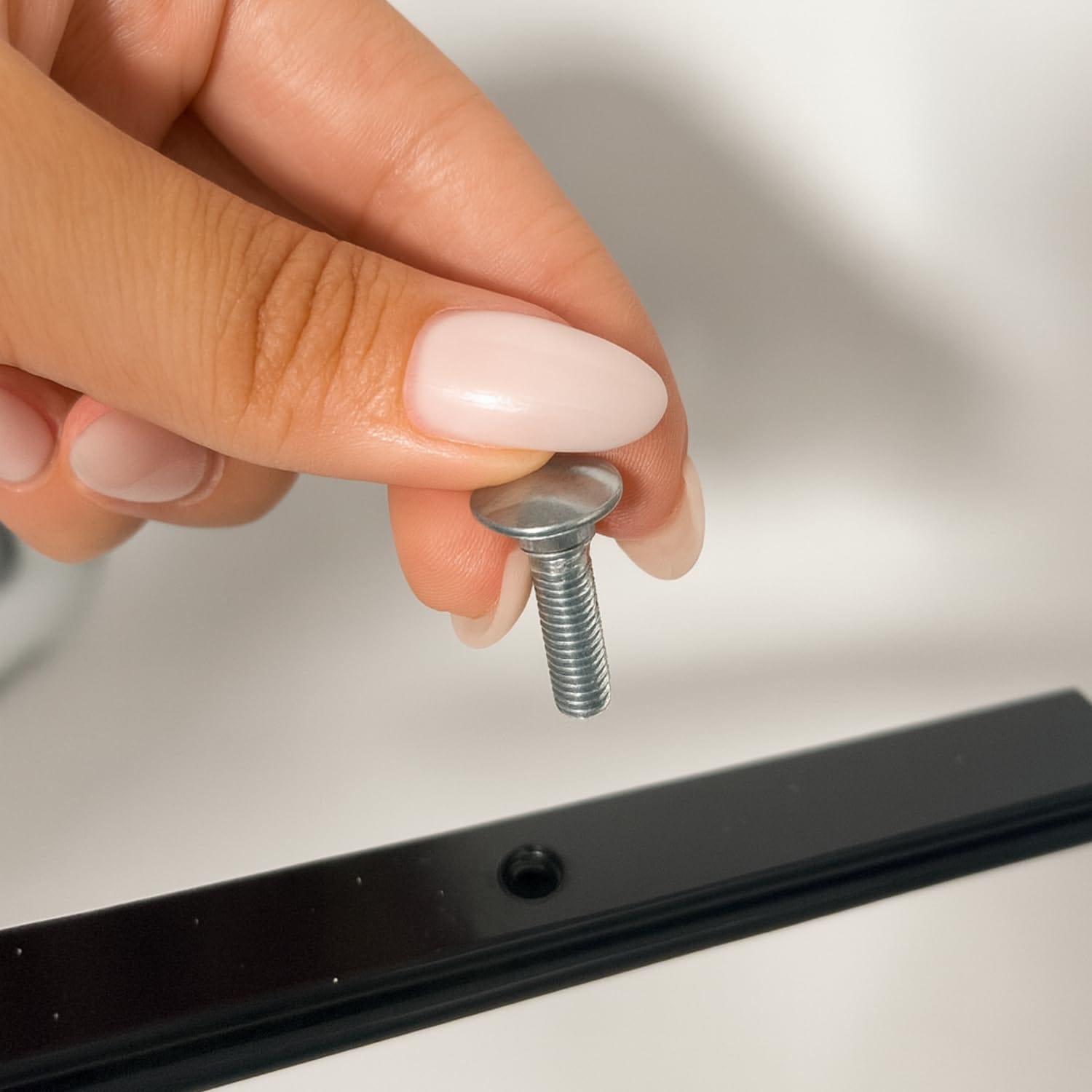 Mano che tiene una vite per montaggio balconiera regolabile in ferro nero da esterno