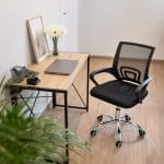 sedia da ufficio nera coreografica Sedia da ufficio ergonomica nera con schienale traspirante in ambiente ufficio moderno con scrivania