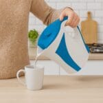 bollitore-elettrico-coreografica-blu Bollitore elettrico blu 1.7L in uso per preparare bevande calde in cucina