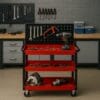 Carrello portautensili rosso e nero in officina con attrezzi e trapano