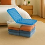 Contenitore salvaspazio trasparente con coperchio blu aperto e biancheria ordinata in camera